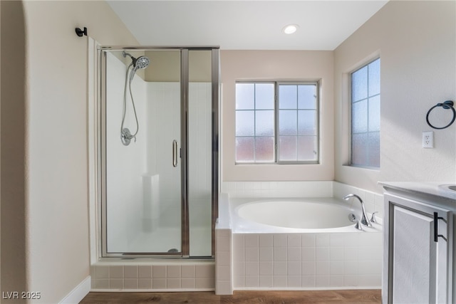 bathroom featuring plus walk in shower, wood-type flooring, and vanity