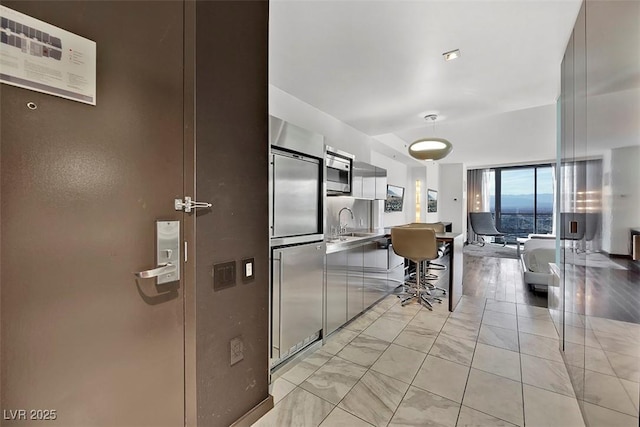 kitchen with built in appliances, sink, and a kitchen breakfast bar