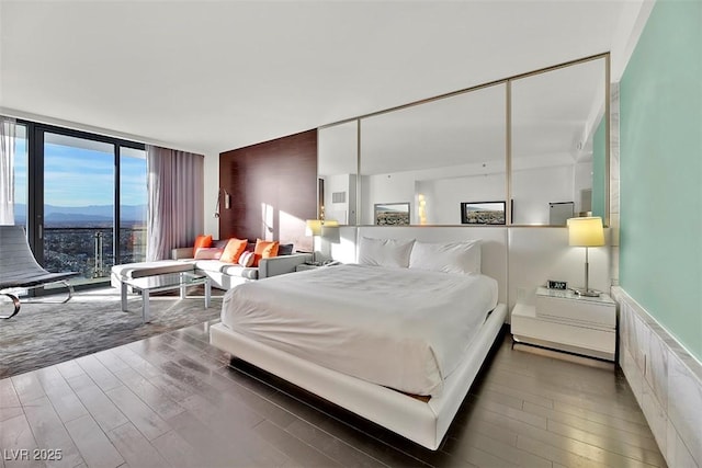 bedroom featuring a wall of windows, dark hardwood / wood-style flooring, and a mountain view