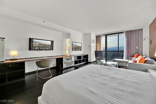 bedroom with expansive windows and hardwood / wood-style floors