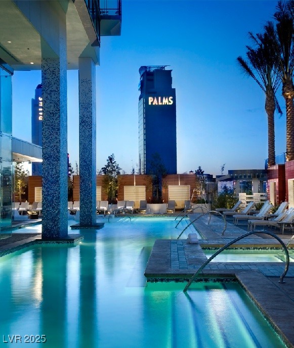 pool at dusk featuring a patio area and a hot tub