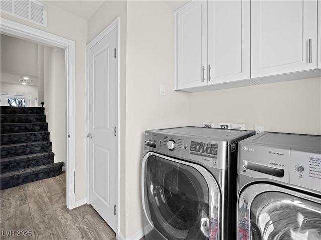 laundry area featuring cabinets, washer and dryer, and light wood-type flooring