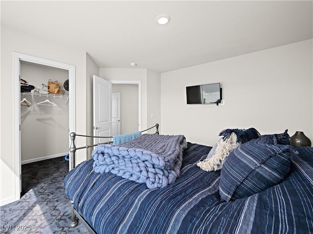 bedroom featuring a walk in closet, a closet, and dark colored carpet