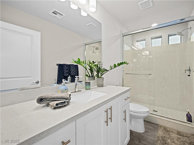 bathroom with hardwood / wood-style flooring, vanity, toilet, and a shower with shower door