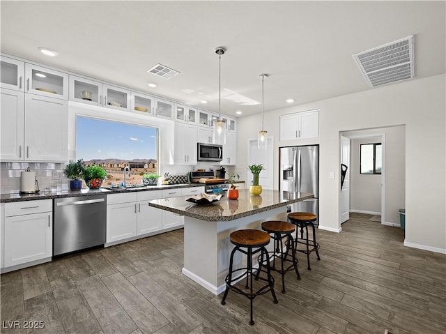 kitchen with sink, white cabinetry, decorative light fixtures, a center island, and stainless steel appliances