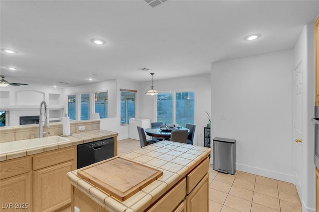 kitchen with sink, tile countertops, black dishwasher, and light brown cabinets