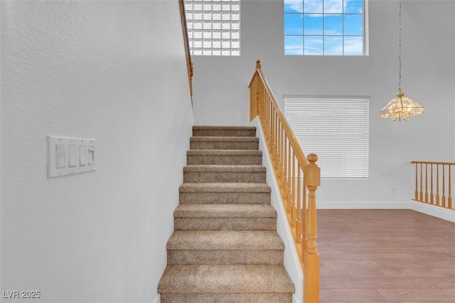 stairway featuring hardwood / wood-style flooring, plenty of natural light, and a high ceiling