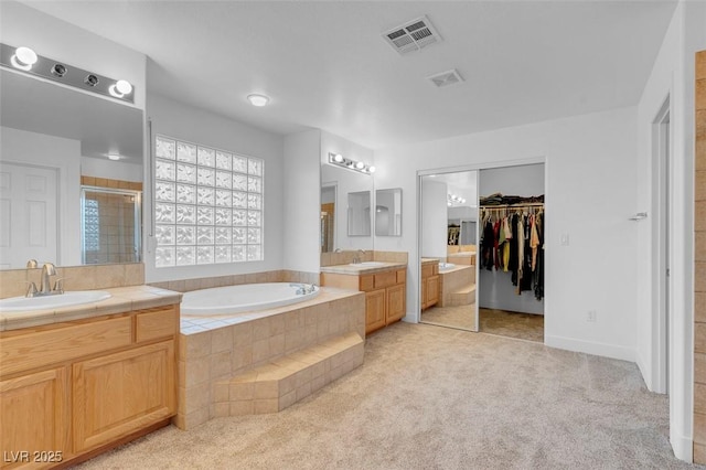 bathroom with vanity and shower with separate bathtub