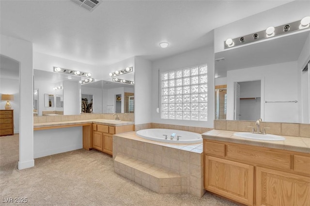 bathroom featuring a garden tub, a stall shower, and two vanities