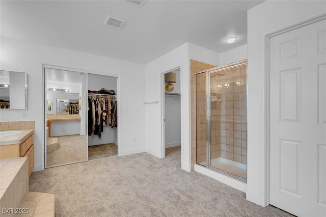 full bathroom with a shower stall, a walk in closet, and vanity