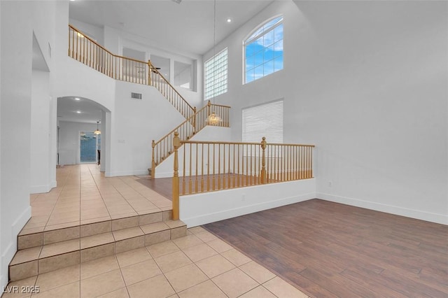 stairway with hardwood / wood-style floors and a towering ceiling