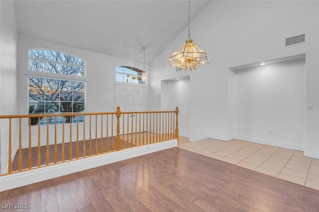 spare room featuring a chandelier, high vaulted ceiling, and light hardwood / wood-style flooring