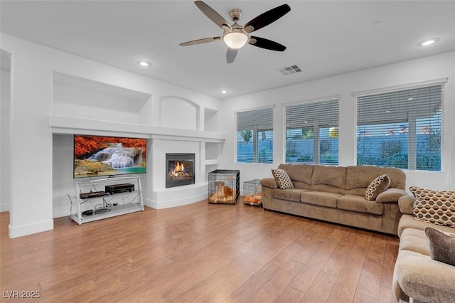 living room featuring ceiling fan, wood-type flooring, and built in features