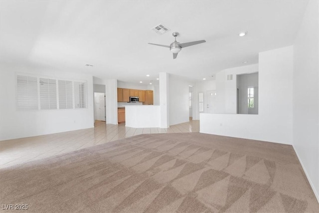 unfurnished living room featuring ceiling fan and light carpet