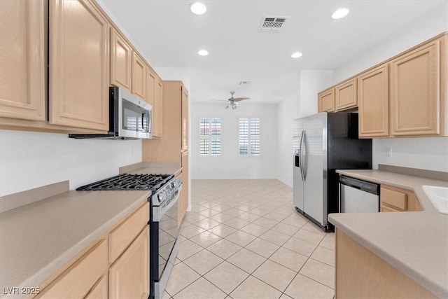 kitchen featuring ceiling fan, appliances with stainless steel finishes, light tile patterned flooring, and light brown cabinetry