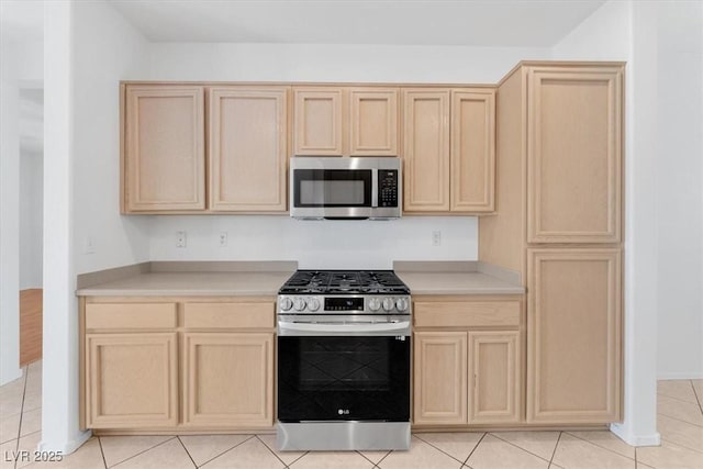 kitchen featuring stainless steel appliances, light tile patterned floors, and light brown cabinets