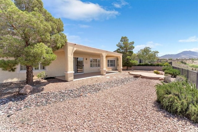 back of property featuring a mountain view and a patio area