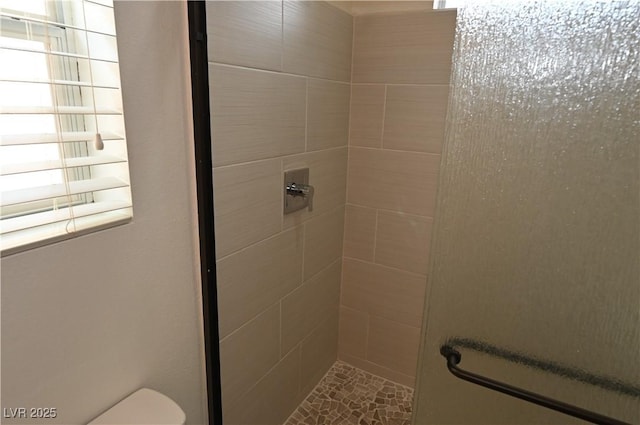 bathroom featuring tiled shower and toilet