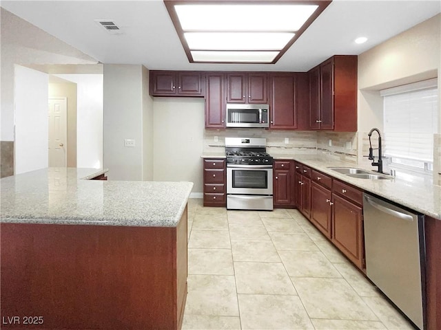 kitchen featuring stainless steel appliances, light stone countertops, sink, and light tile patterned floors