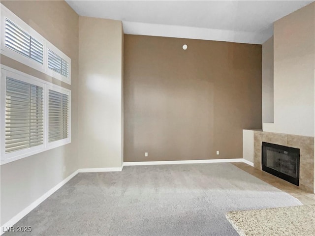 unfurnished living room featuring a tile fireplace and light colored carpet