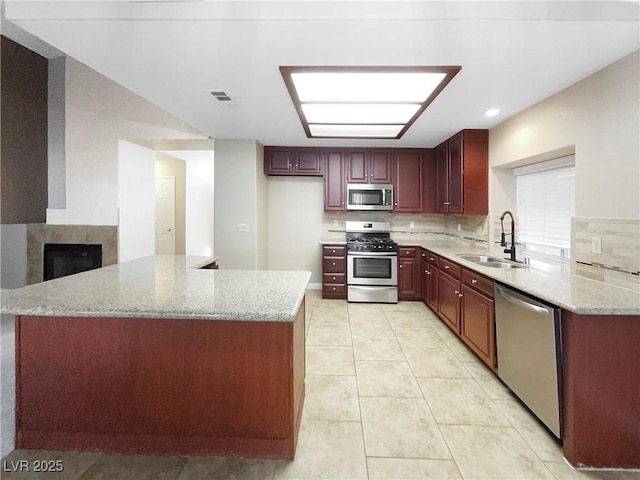 kitchen with stainless steel appliances, light stone countertops, sink, and light tile patterned floors