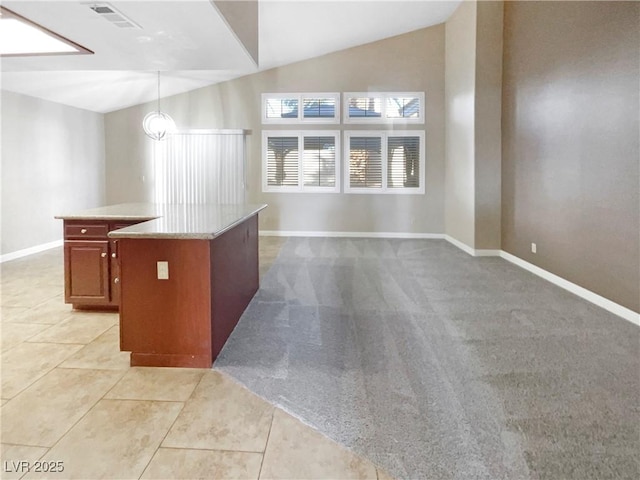 kitchen with vaulted ceiling, a kitchen island, light tile patterned floors, and decorative light fixtures