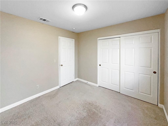 unfurnished bedroom with light carpet and a closet