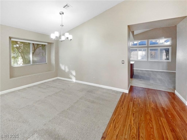 empty room featuring vaulted ceiling, wood-type flooring, and a chandelier