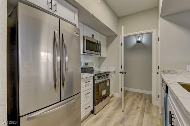 kitchen with light stone counters, stainless steel appliances, light hardwood / wood-style flooring, and white cabinets