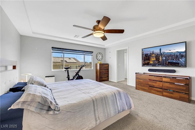 bedroom with ceiling fan, a tray ceiling, and carpet