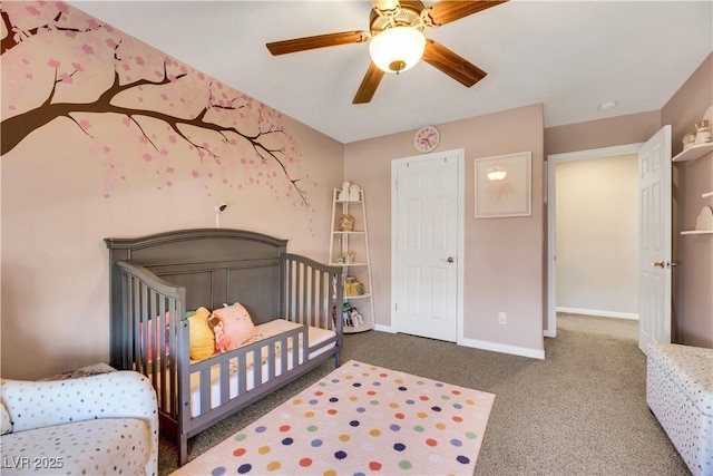 carpeted bedroom with ceiling fan and a crib