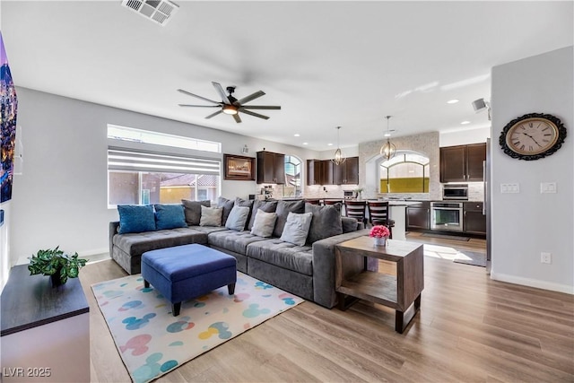 living room with light hardwood / wood-style flooring and ceiling fan