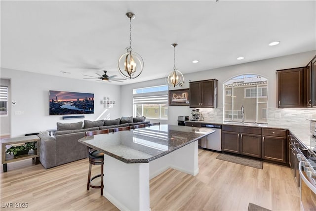 kitchen with sink, backsplash, a kitchen breakfast bar, a kitchen island, and stainless steel dishwasher