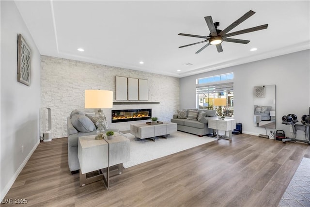 living room with a large fireplace, hardwood / wood-style floors, and ceiling fan