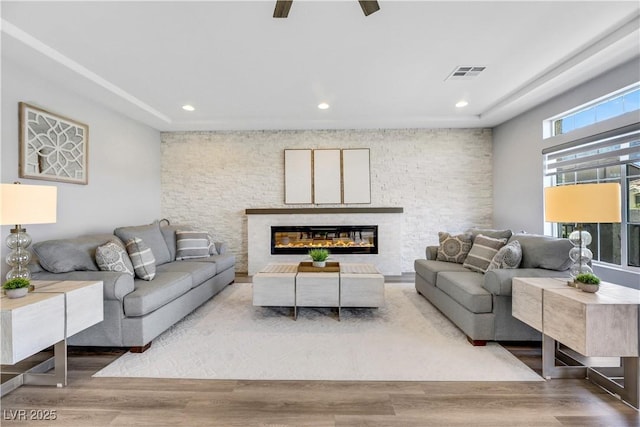 living room featuring a stone fireplace and hardwood / wood-style floors