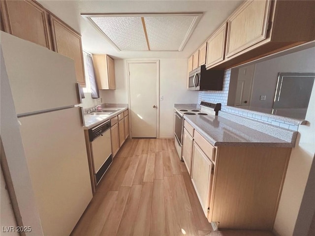 kitchen with light brown cabinetry, tasteful backsplash, sink, light wood-type flooring, and white appliances