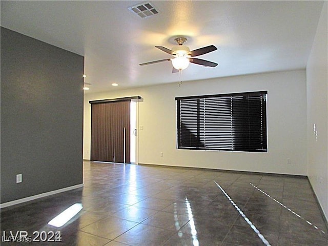 tiled empty room featuring ceiling fan