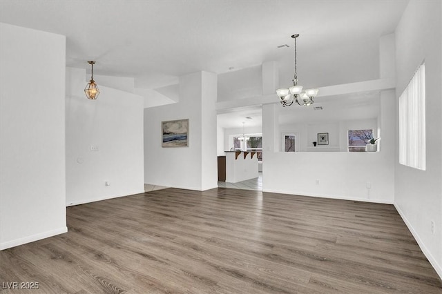 unfurnished living room with an inviting chandelier, hardwood / wood-style flooring, and a wealth of natural light