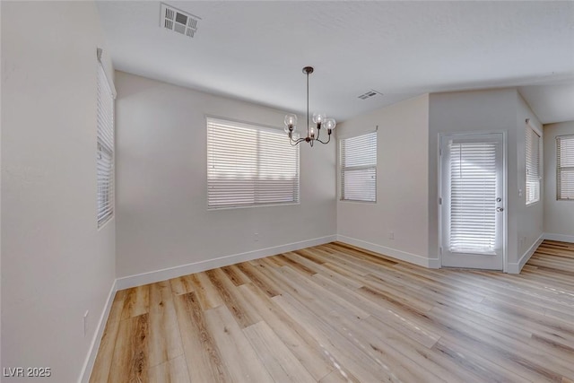 unfurnished dining area featuring a chandelier and light hardwood / wood-style flooring