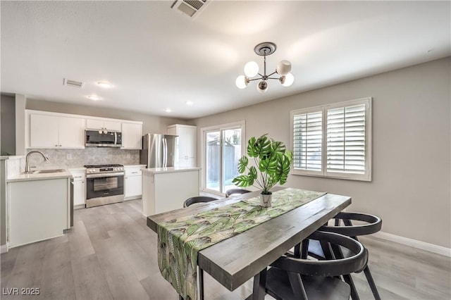 dining space featuring an inviting chandelier, sink, and light wood-type flooring