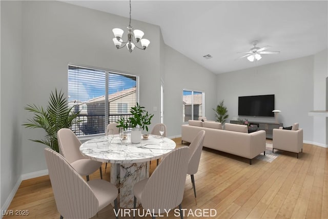 dining room featuring light wood finished floors, a wealth of natural light, and ceiling fan with notable chandelier