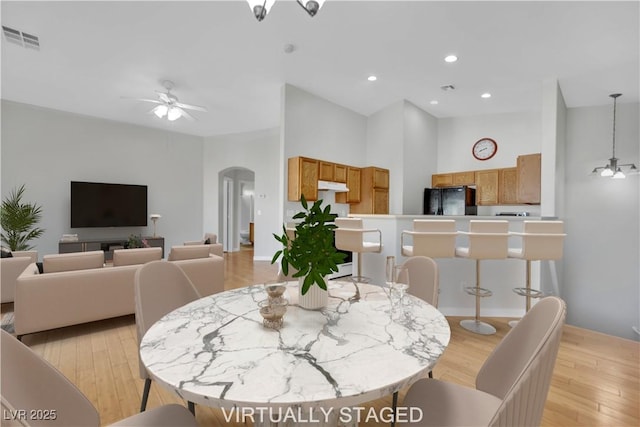 dining area with light wood-style floors, visible vents, arched walkways, and a ceiling fan