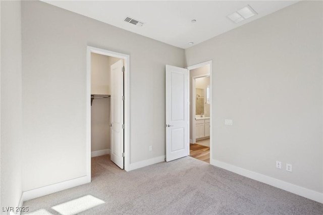 unfurnished bedroom with a spacious closet, light colored carpet, and a closet