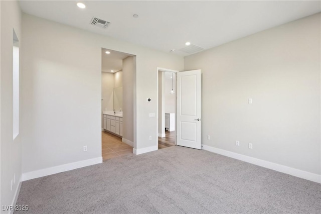 unfurnished bedroom with connected bathroom and light colored carpet