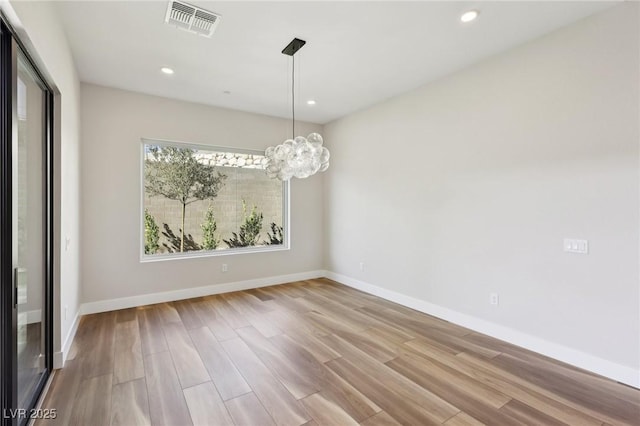 unfurnished dining area featuring an inviting chandelier and light wood-type flooring