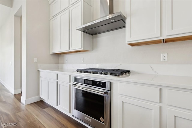 kitchen featuring appliances with stainless steel finishes, light hardwood / wood-style flooring, white cabinets, and wall chimney exhaust hood