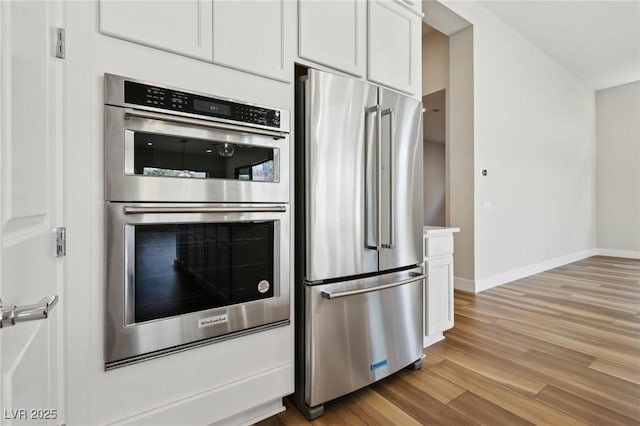 kitchen with light hardwood / wood-style floors, white cabinets, and appliances with stainless steel finishes