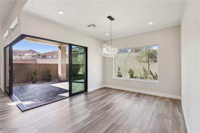 unfurnished dining area with hardwood / wood-style flooring and an inviting chandelier