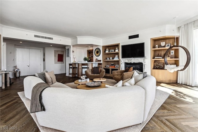 living room with a fireplace, dark parquet floors, and built in shelves