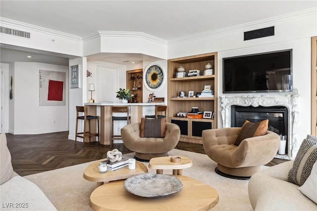 living room with crown molding, dark parquet flooring, a high end fireplace, and built in features